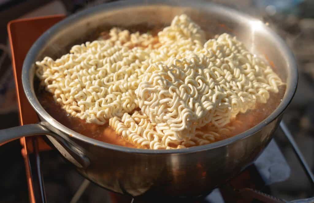Instant ramen cooking on a stove with seasoning