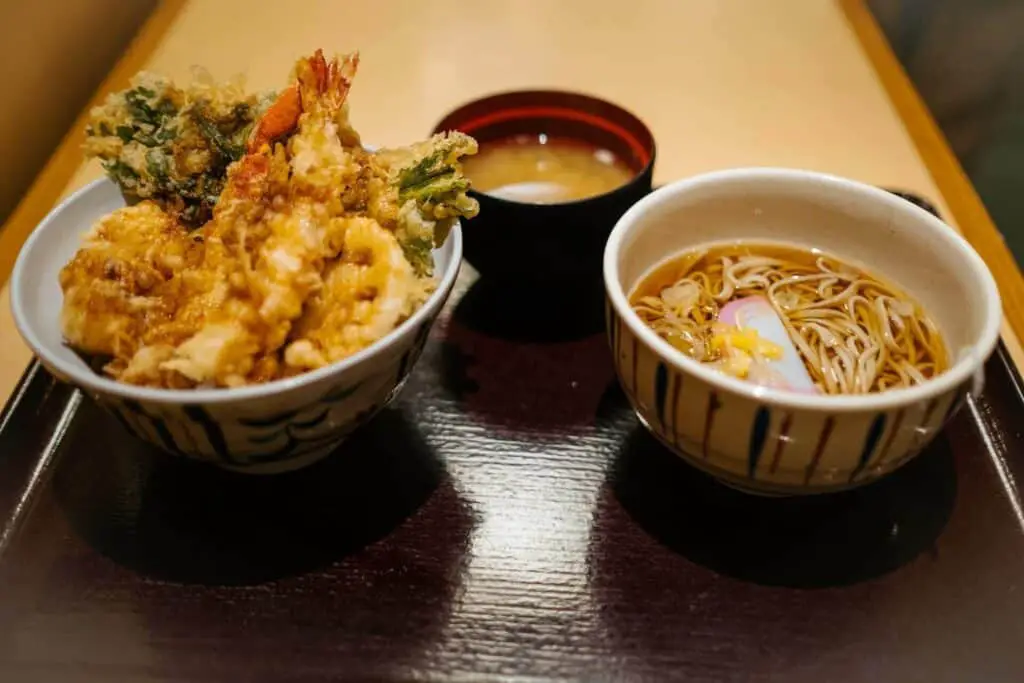 Bowl of shrimp tempura, a bowl of noodles, and a bowl of soup on the tray
