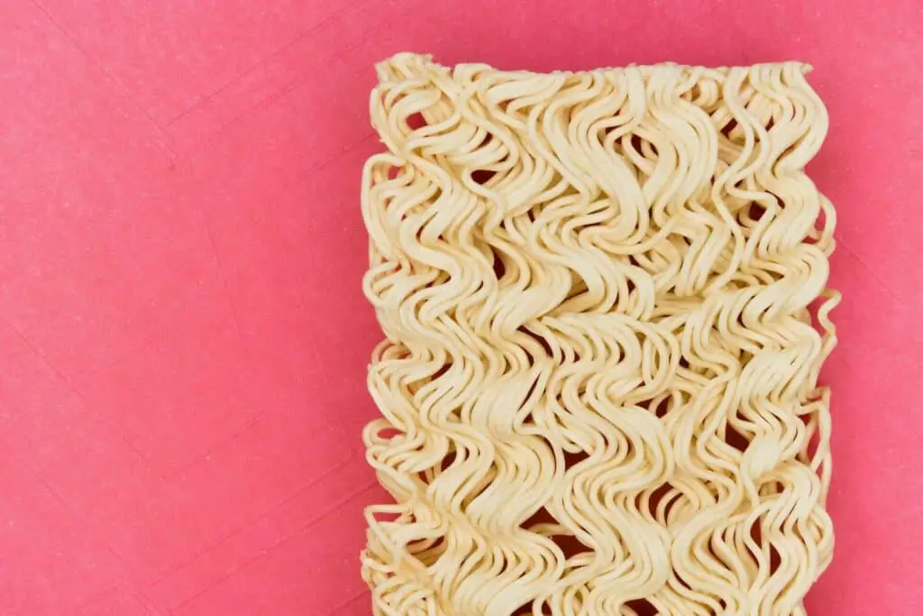Unprepared instant ramen noodles on a pink surface