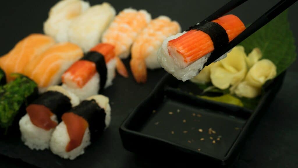 Someone holding a crab nigiri with chopsticks