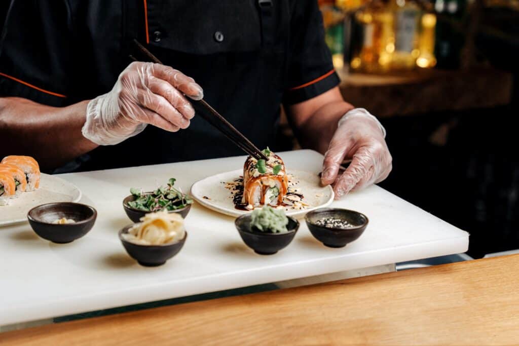 A chef off-screen plating sushi