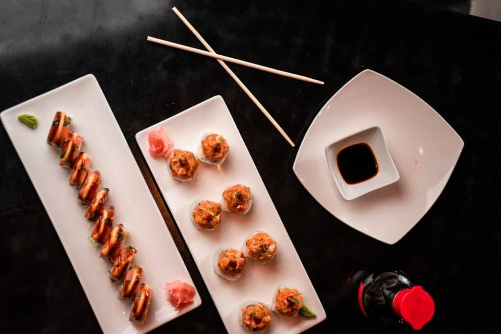 Lined up sushi rolls and a small dish with wasabi sauce