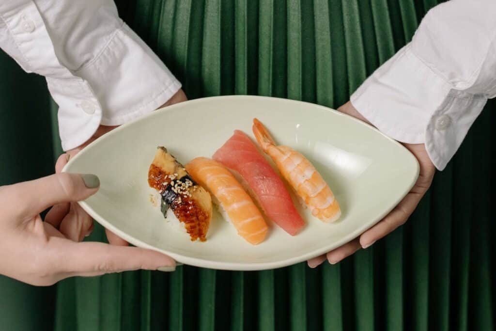 Some nigiri pieces plated and held by a woman off-screen