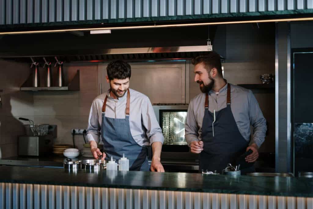 Two chefs preparing a meal sous vide and laughing about something