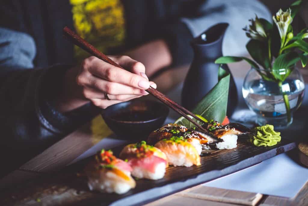 A woman eating sushi with chopsticks