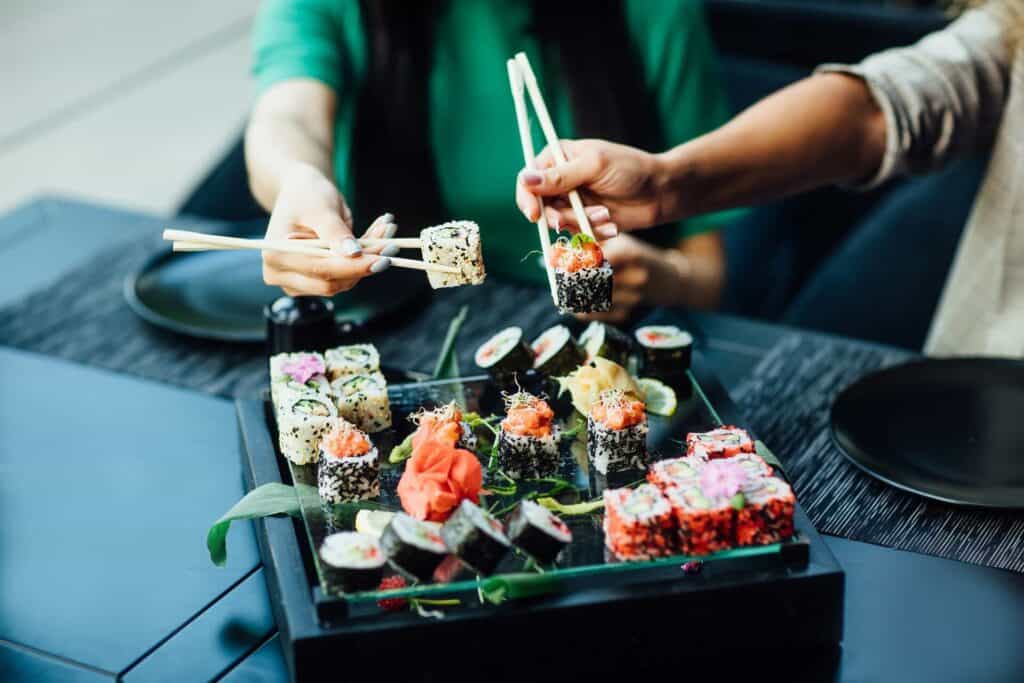 People eating sushi with chopsticks 
