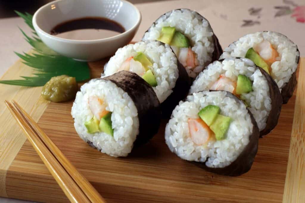 A maki sushi roll cut into smaller pieces and served on a wooden plate