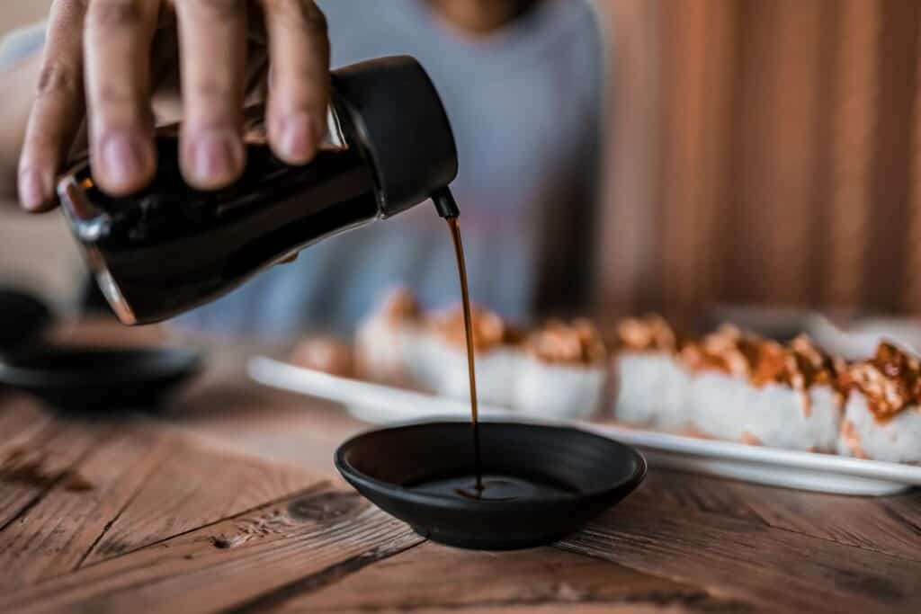 Person pouring the soy sauce into the bowl
