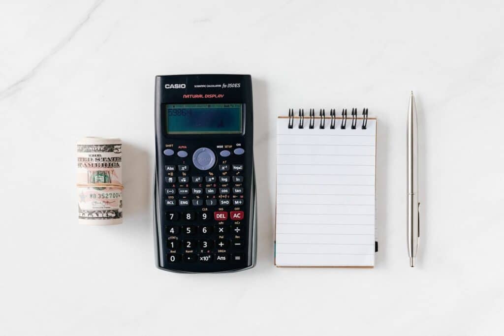 Calculator between money and notebook with pen