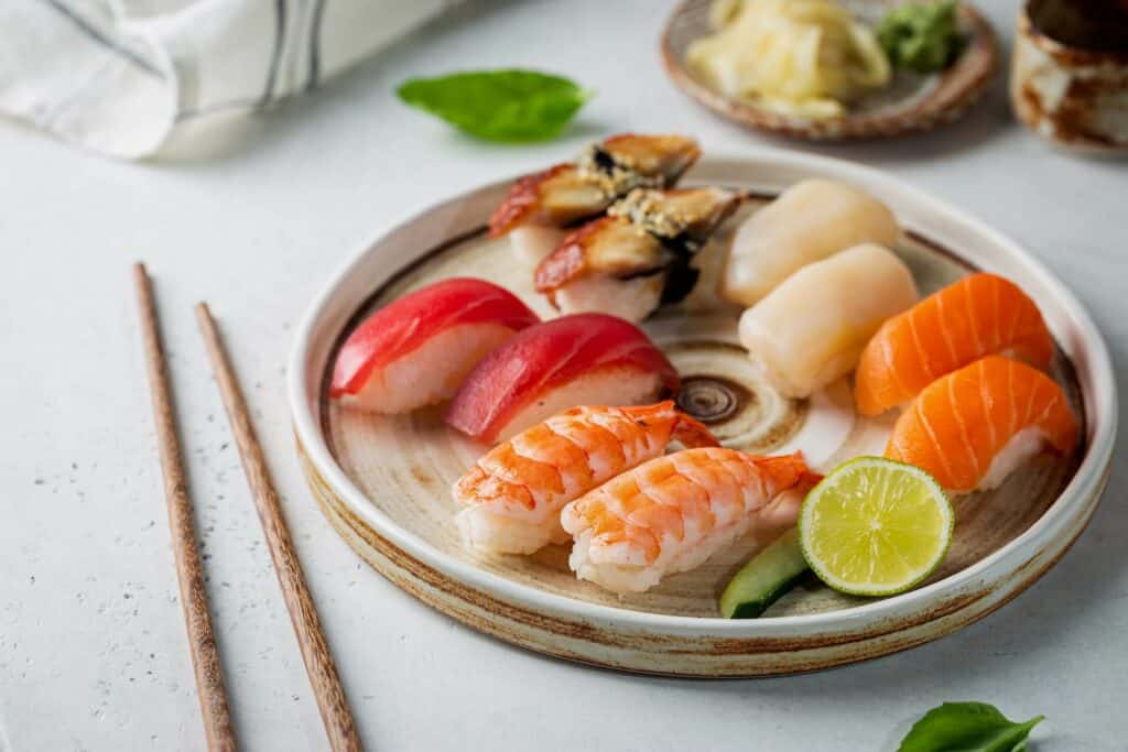  Nigiri sushi rolls on a plate with chopsticks next to it
