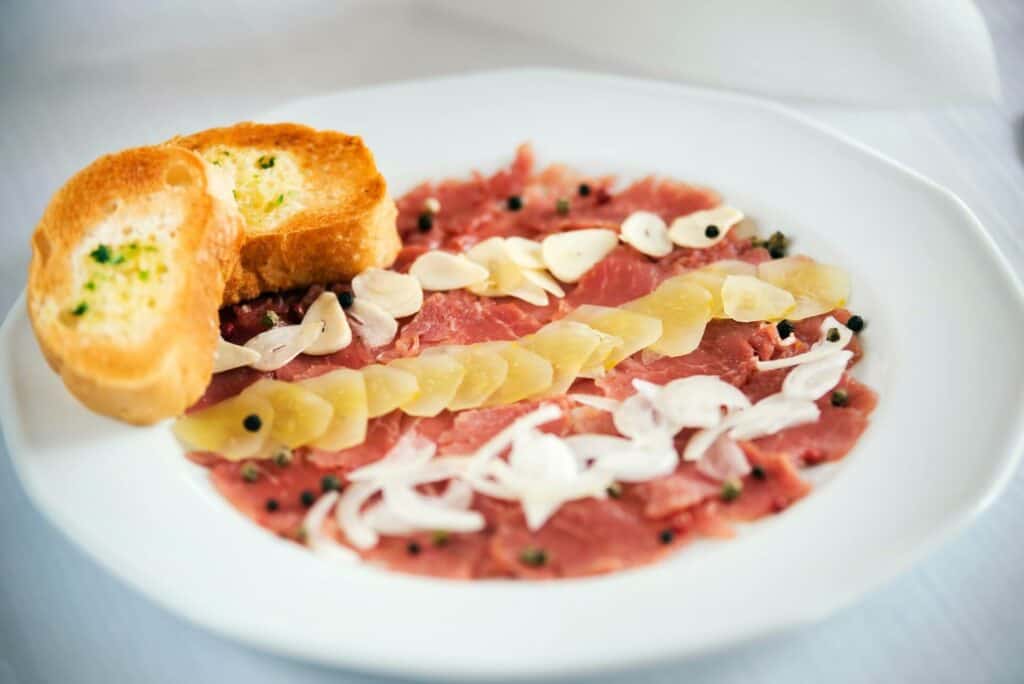 Carpaccio served on a plate with garnish and toasted bread