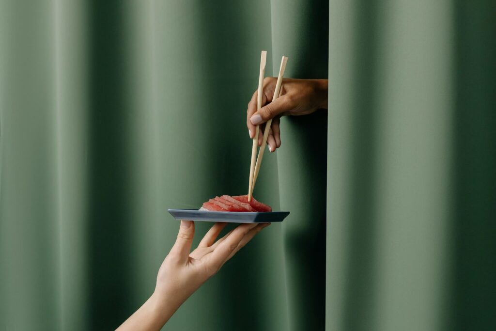 A person holding a plate with sashimi