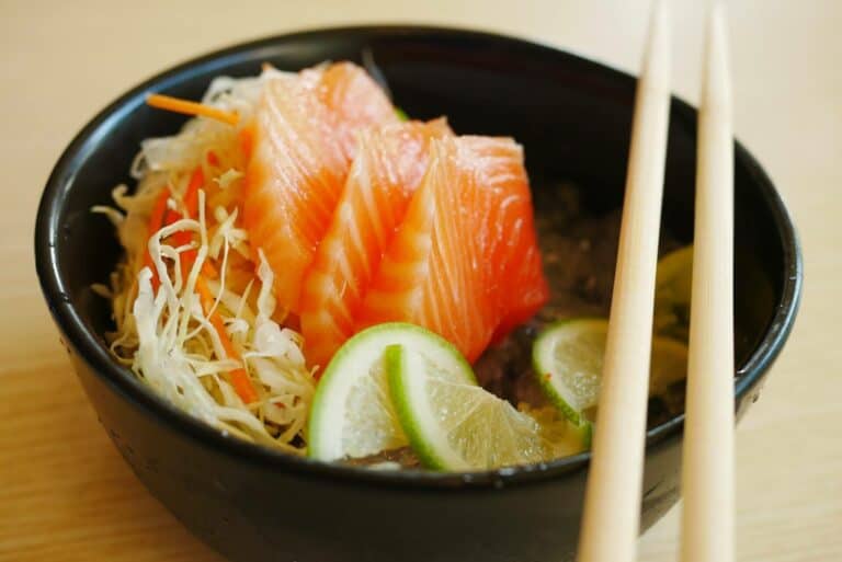 Slices of salmon sashimi in a black bowl
