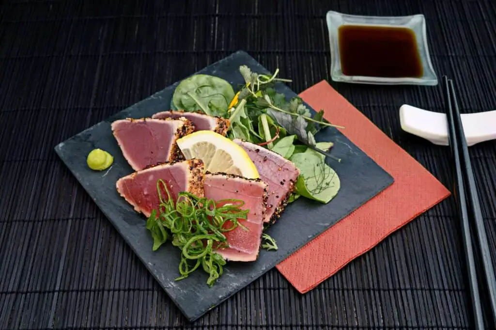 Tuna with lemon and greens on a black platter