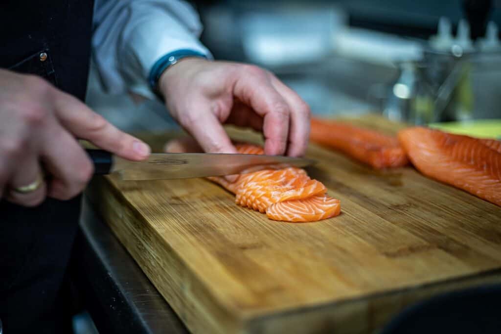 A chef cutting raw salmon