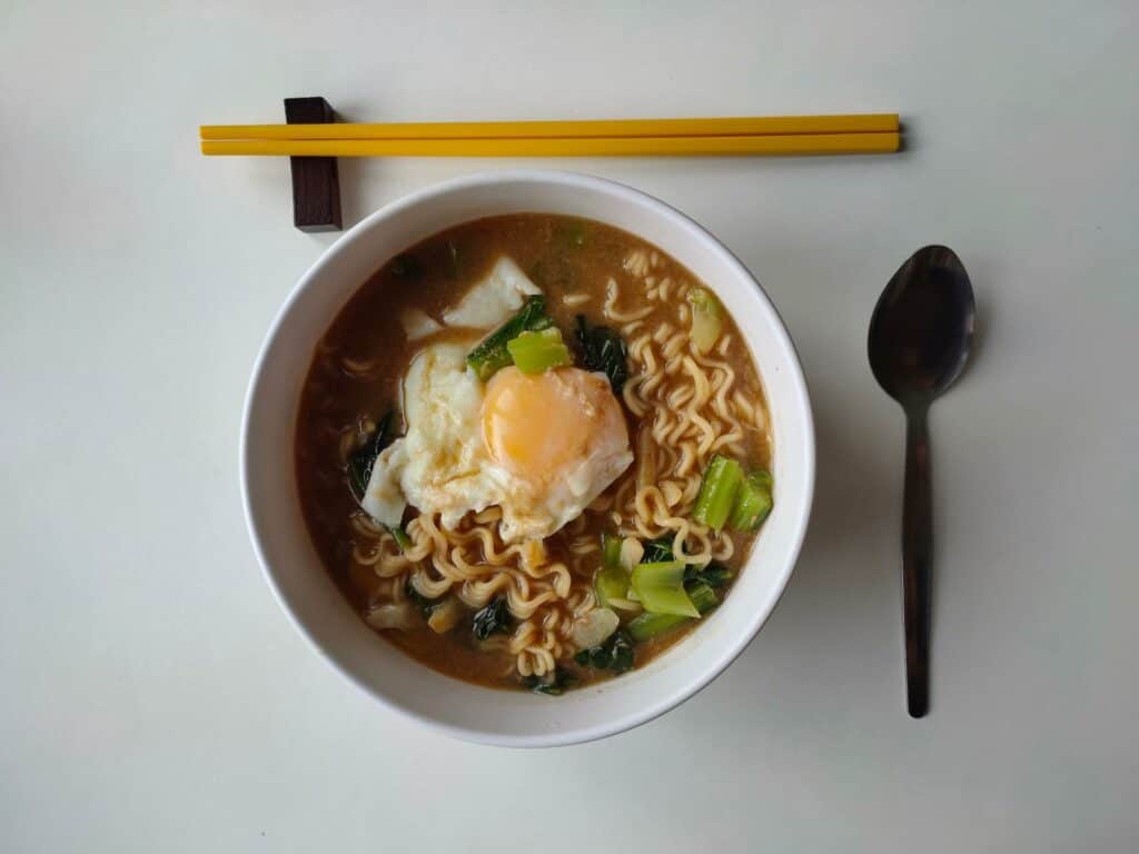 A bowl of ramen with chopsticks and a spoon
