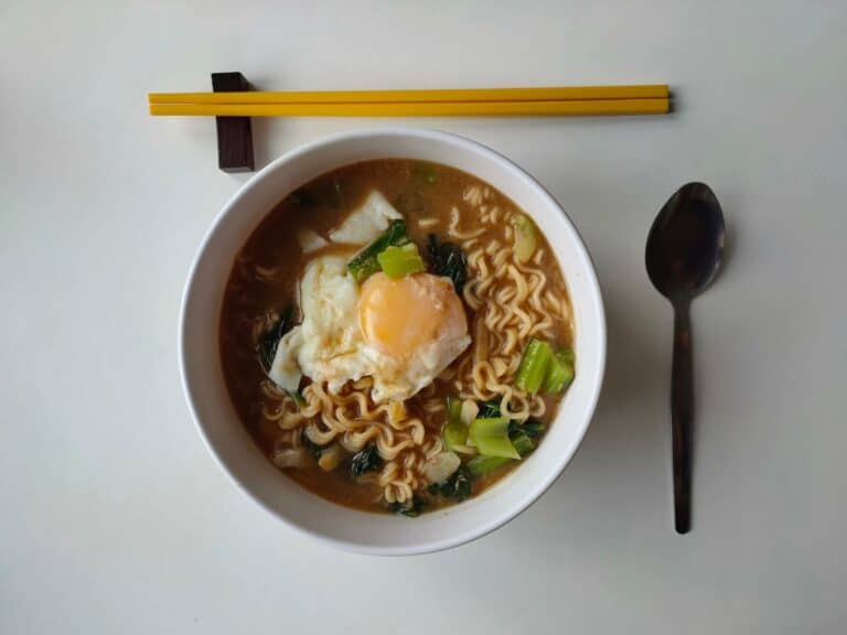 Ramen soup next to chopsticks and a spoon