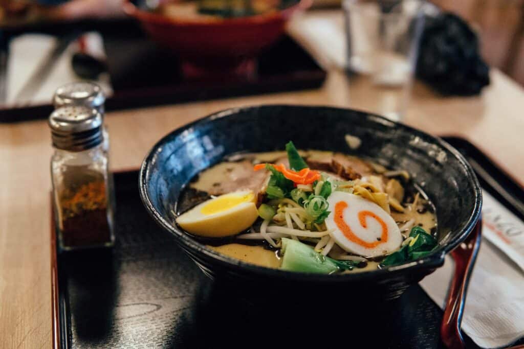 A bowl of ramen with egg, radish, and vegetables