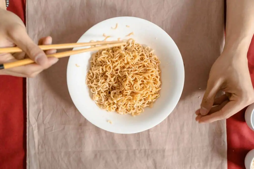 A person holding chopsticks over a bowl of ramen