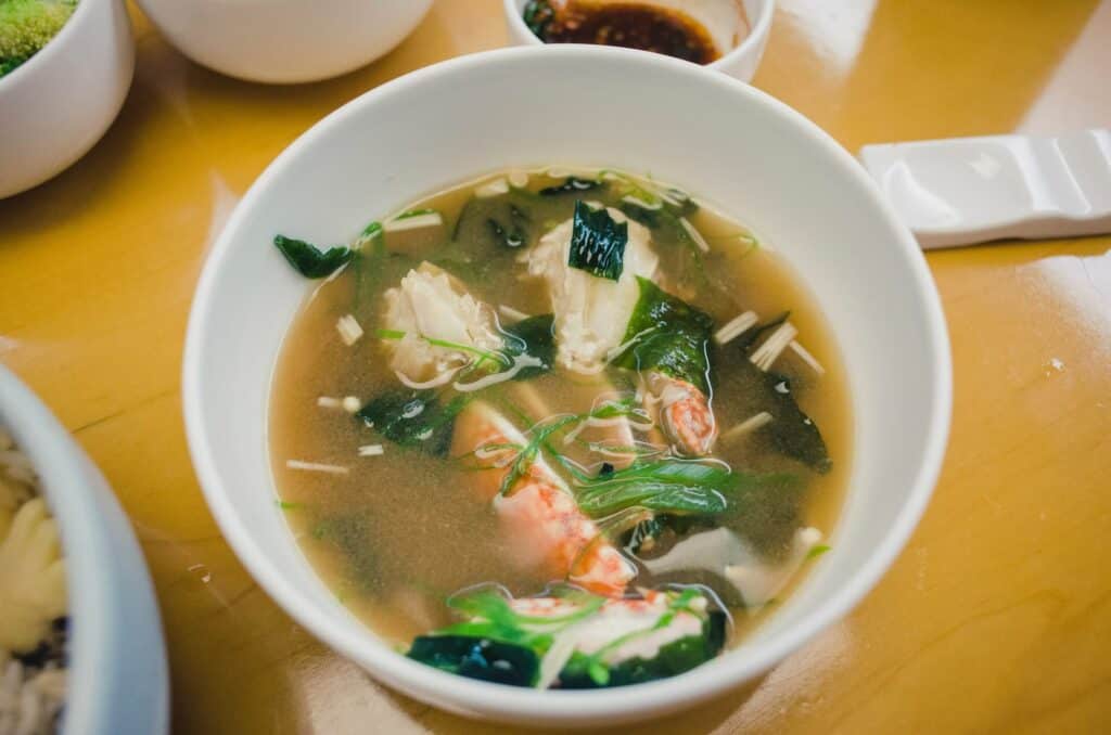 A bowl of miso soup with seaweed and shrimp