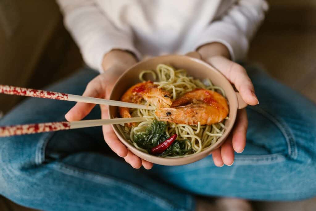 Person holding a bowl with ramen 
