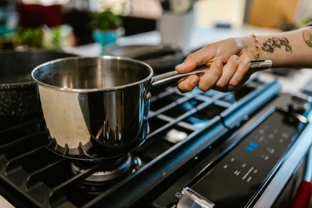 A person off-screen placing a pot on the stove