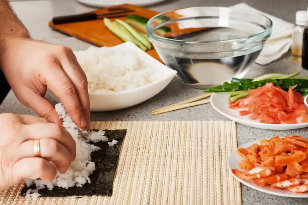 A person off-screen making sushi rolls