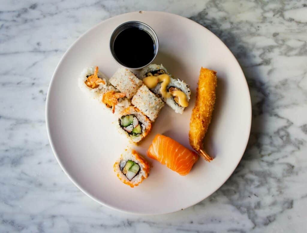 Plate with tempura, a little bowl of sauce, and a few pieces of sushi 