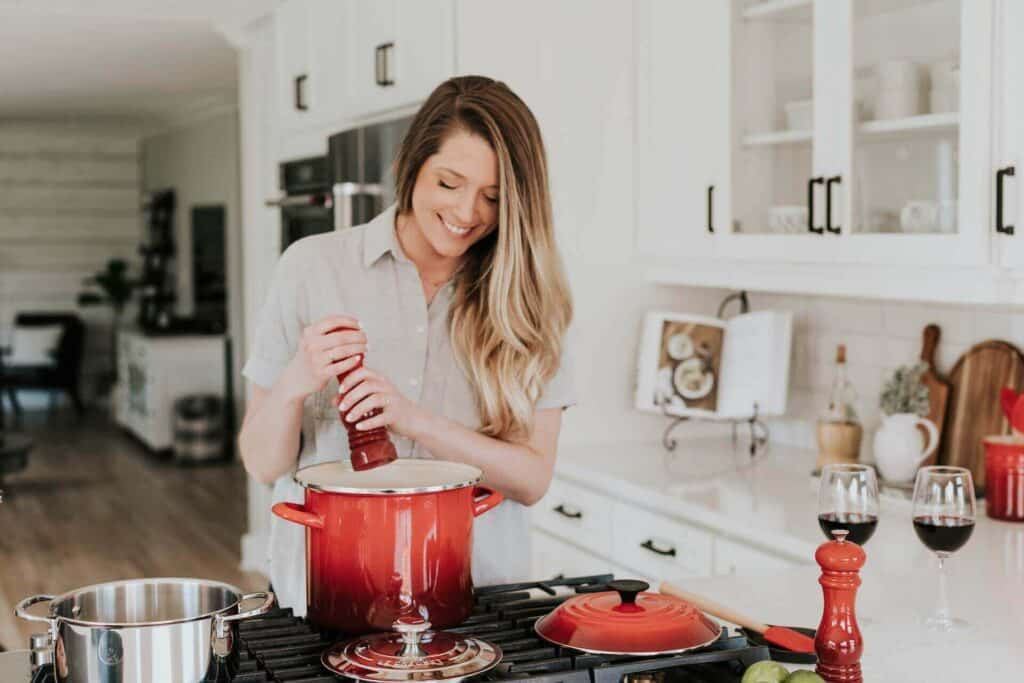 Woman adding seasoning to a pot