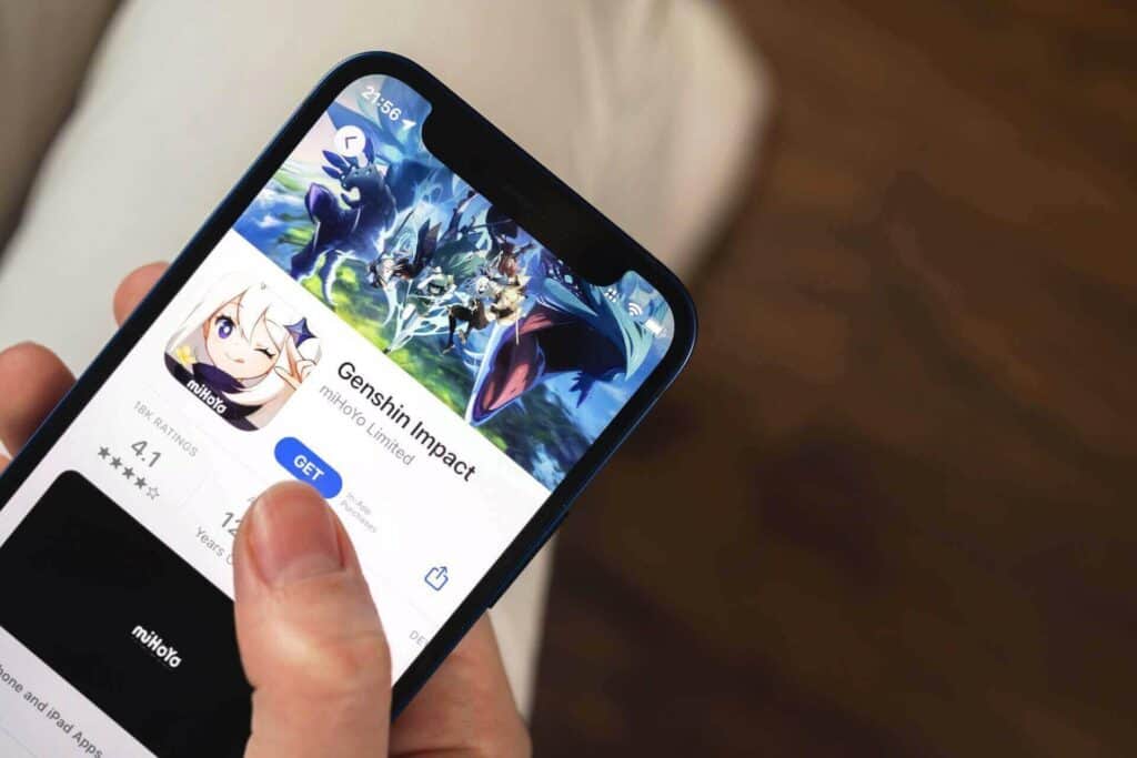 Person tapping on Genshin Impact game on phone