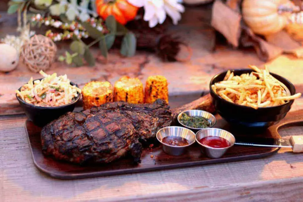 A rib eye with some fries and sauce