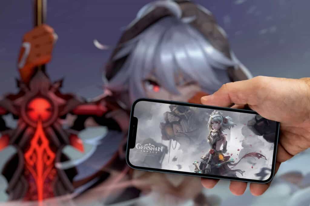 Man holding a phone with Genshin Impact game