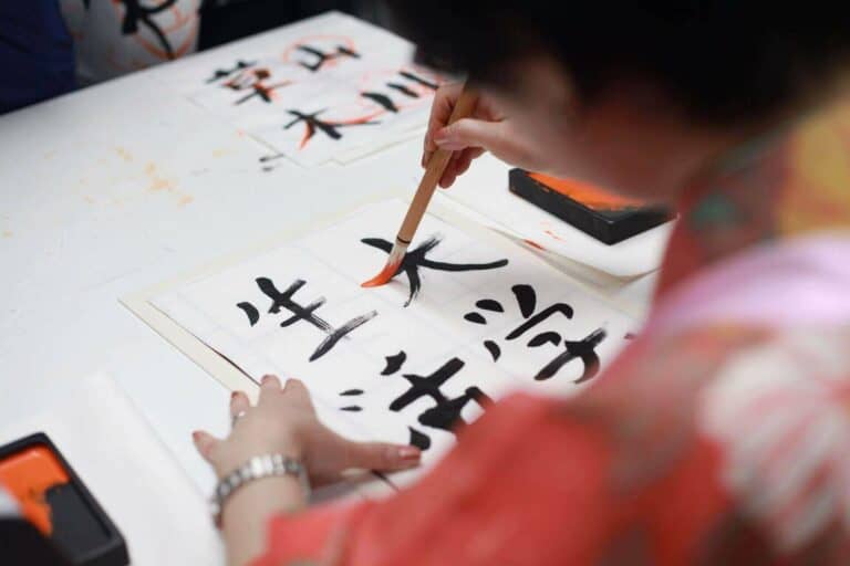 A woman writing kanji with a brush